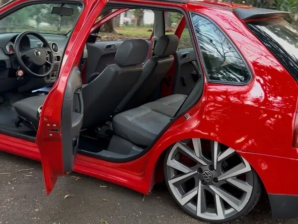 Gol G4 vermelho com a porta aberta mostrando bancos e roda aro 18