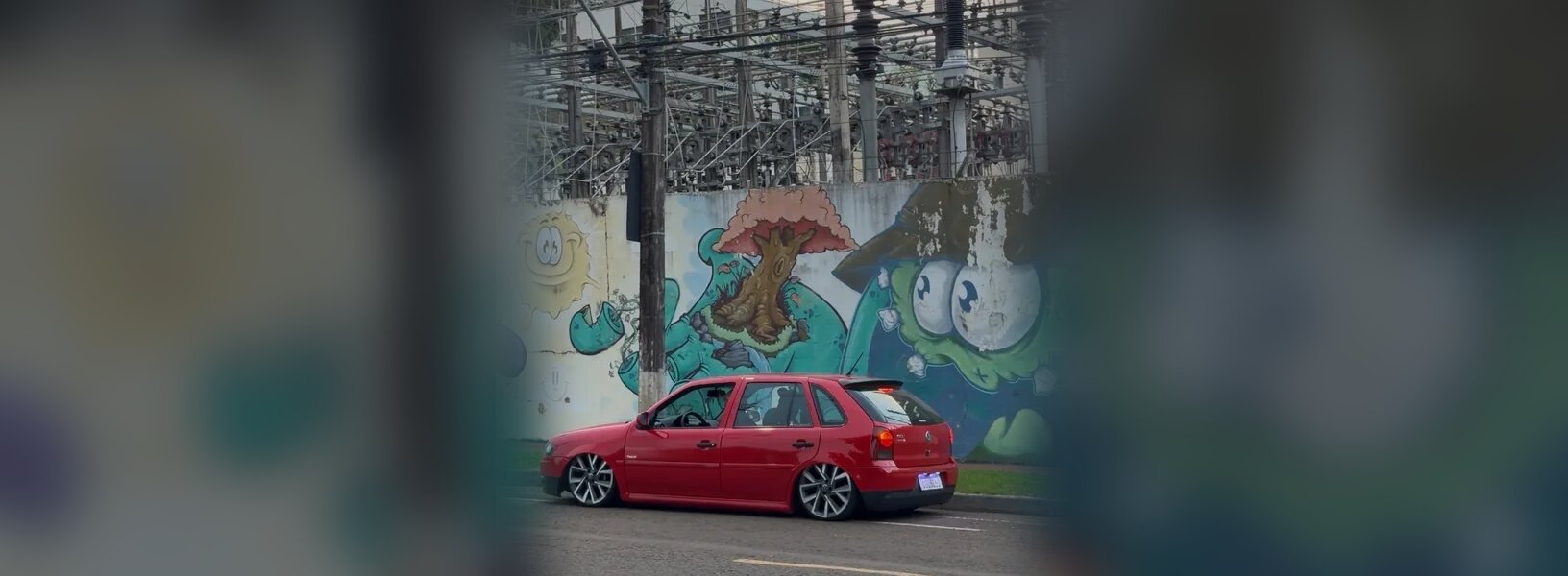 Gol G4 vermelho rebaixado diante de um muro grafitado